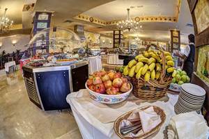 Buffet im Restaurant des Bull Hotel Reina Isabel & Spa mit Obst, Geschirr und Servietten.