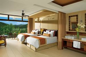 Schlafzimmer im Dreams Las Mareas Costa Rica mit zwei Betten, Balkon, Deckenventilator und Blick auf die Berge.