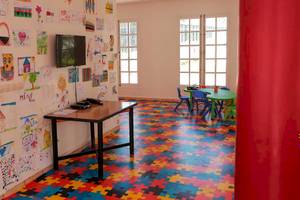 Spielzimmer im Allegro Agadir Hotel mit buntem Puzzleboden, Fernseher an der Wand, Schreibtisch und bunten Stühlen.
