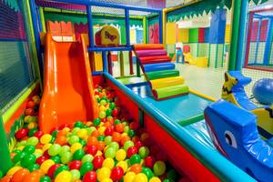 Spielplatz im Tagoro Family & Fun Costa Adeje mit vielen bunten Bällen und einem großen orangefarbenen Rutsch.