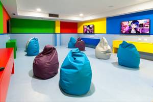 Spielzimmer im Tagoro Family & Fun Costa Adeje mit bunten Wänden, mehreren Fernsehgeräten und bunten Beanbags.