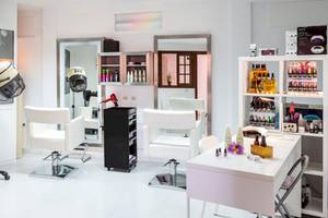 Friseursalon im Hotel Tagoro Family & Fun Costa Adeje mit weißen Stühlen und Geräten.