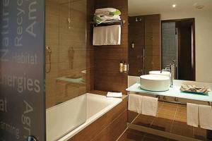 Badezimmer im Neya Lisboa Hotel mit Badewanne, Waschbecken und Handtüchern.