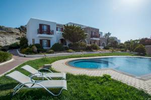 Das Naxos Palace Hotel mit einem Pool und Liegen auf dem Rasen.