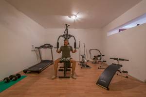 Fitnessraum im Naxos Palast Hotel mit einem Mann, der ein Liegestützgerät benutzt.