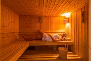 Frau liegt entspannt in einer Holzsauna