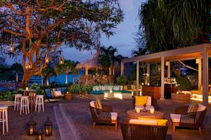 Außenbereich des Secrets Papagayo Costa Rica Hotels mit Beleuchtung, Möbeln und Blick auf den Ozean.