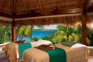 Zwei Massageliegen im Freien mit Blick auf das Meer am Secrets Papagayo Costa Rica Hotel.
