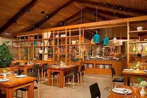 Innenraum des Restaurants Secrets Papagayo Costa Rica mit Holztischen, Stühlen und offenen Regalen.