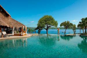 Unendlicher Pool am Secrets Papagayo Costa Rica mit Blick auf das Meer und eine Hütte.