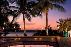 Ein Paar genießt ein Abendessen am Swimmingpool im Secrets Papagayo Hotel bei Sonnenuntergang.