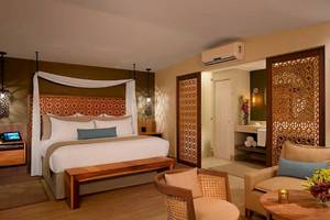 Suite im Secrets Papagayo Costa Rica mit Doppelbett, Wohnzimmerbereich und modernem Dekor.