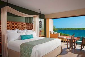 Suite mit Meerblick im Secrets Papagayo Costa Rica Hotel, inklusive Bett, Sitzbereich und Meersicht.