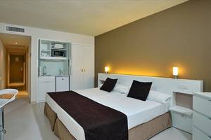 Hotelzimmer des Sol Wave House All Suites mit Doppelbett, Fernseher, und Küchenzeile.