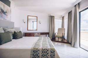 Hotelzimmer im Iberostar Origin Bella Costa mit Bett, Nachttisch und Aussicht.