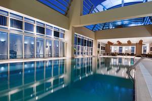 Innenpool des Grand Millennium Al Wahda Hotels bei Nacht mit Stadtblick