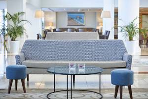 Lobby des Louis Ledra Beach Hotels mit Sofa, Tisch und Pflanzen.