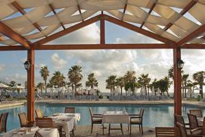Terrasse des Louis Ledra Beach Hotels mit Blick auf den Pool und das Meer.