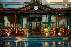 Pool Terrasse im Louis Ledra Beach Hotel mit Tischen, Stühlen und Pflanzen.