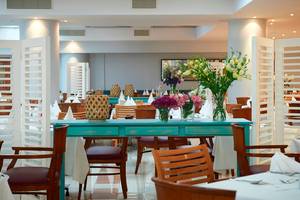 Innenansicht des Restaurants im Louis Ledra Beach Hotel mit blauem Tisch und Blumenvasen.