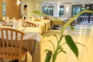 Innenansicht des Restaurants im Minos Mare Hotel mit gedeckten Tischen und Stühlen.