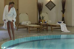 Eine Frau im Bademantel steht am Pool im Minos Mare Hotel.