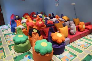 Viele bunte Kissen und Sitzsäcke sind in einem Raum angeordnet, auf einem gemusterten Boden.