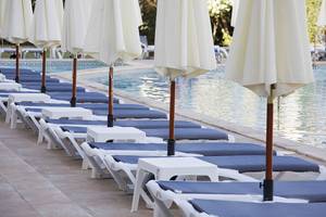 Reihe von weißen und blauen Liegestühlen am Pool des Alua Leo Hotels