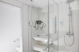 Badezimmer im Alua Leo Hotel mit Glasdusche, Waschbecken und Toilette.