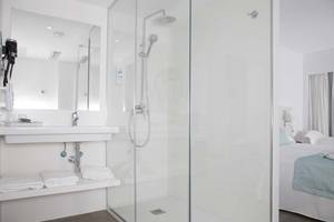 Badezimmer im Alua Leo Hotel mit Duschkabine, Waschbecken und Bett