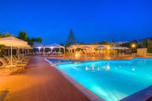 Poolbereich im Solimar Dias Hotel bei Nacht mit beleuchteten Schirmen und Lounge-Stühlen.