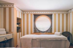 Massageraum im Iberostar Laguna Azul Hotel mit Rundfenster und gestreiften Wänden.