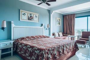 Ein Hotelzimmer im Iberostar Laguna Azul Hotel mit einem Bett, Nachttischen, Lampen und einem Balkon.
