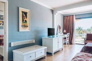 Innenansicht eines Hotelzimmers im Iberostar Laguna Azul, mit zwei Betten, Fernseher, Schreibtisch und Balkon.