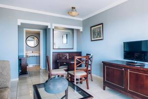 Wohnzimmer des Iberostar Laguna Azul Hotels mit Fernseher, Esstisch und Stühlen.