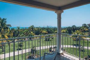 Aussicht von Balkon des Iberostar Laguna Azul Hotels auf einen Rasen und Palmen mit Blick auf das Meer.