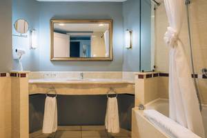 Badezimmer im Iberostar Laguna Azul Hotel mit Spiegel, Waschbecken, Handtüchern und Badewanne.
