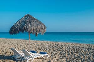 Strand des Iberostar Laguna Azul Hotels mit zwei Sonnenliegen und einem Strohschirm.