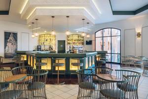Bar im Iberostar Laguna Azul Hotel mit grüner Theke, hängenden Lampen und modernen Möbeln.