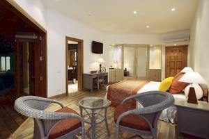 Hotelzimmer im Adaaran Club Rannalhi mit zwei Sessel, Schreibtisch, Bett und Fernseher.