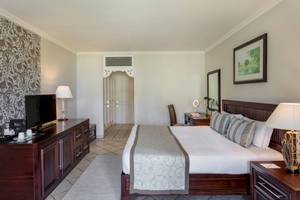 Ein elegantes Hotelzimmer im Sugar Beach Mauritius mit einem großen Bett, Fernseher, und Nachttischen.