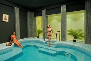 Zwei Frauen im roten Bikini entspannen in einem blau gefliesten Innenpool des Amphoras Beach Hotels.