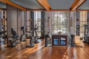 Fitnessbereich im Hotel Chedi Muscat mit Geräten und Fenstern.