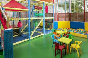 Kinderspielplatz im H10 Las Palmeras mit Klettergerüst, Ballgrube und bunten Tischen und Stühlen.