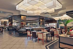 Innenansicht des Restaurants des H10 Las Palmeras Hotels mit geometrischen Deckenleuchten, Buffet und gedeckten Tischen.