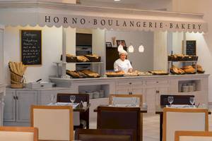 Eine Bäckerei im H10 Las Palmeras Hotel mit einer Köchin, die Gerichte serviert.
