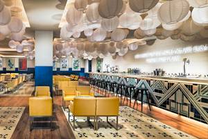 Loungebereich des H10 Las Palmeras Hotels mit gelben Sesseln, weißen Lampions und einer Theke.