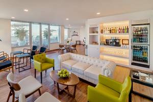 Lobby-Lounge des H10 Las Palmeras Hotels mit weißen Ledersofa, farbigen Sesseln und modernem Design.