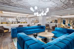 Lobby des H10 Las Palmeras Hotels mit blauen Sofas, Kronleuchter und modernem Design.