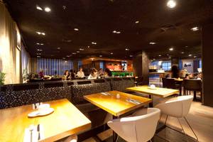 Innenansicht des Restaurants im XO Hotels Blue Tower mit Gästen an Tischen und einer Theke.